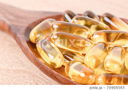 Fish oil capsules in wooden spoon. Fish oil capsules in wooden spoon. 70908565