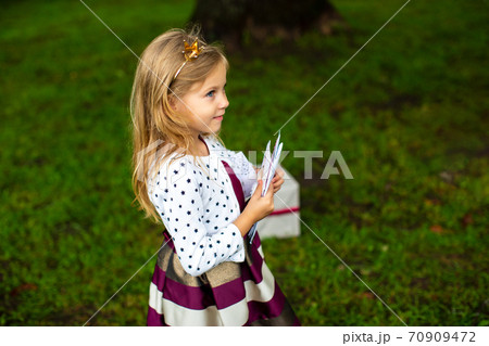 little girl with a crown on her head in festive clothes holds gift envelopes in her hands 70909472