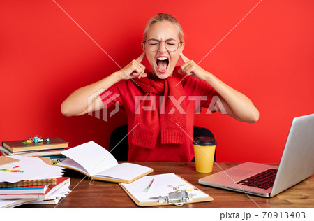 angry young caucasian woman sit at desk with laptop pc covering ears with fingers screaming 70913403