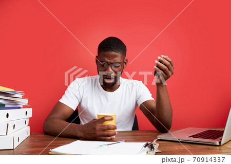 surprised black guy look at empty cup with shock 70914337