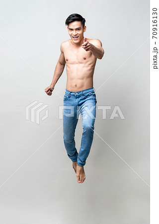Full length portrait of handsome shirtless Asian man jumping and doing thumbs up 70916130