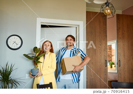 positive smiling couple moving in new house and carrying carton boxes positive smiling couple moving in new house and carrying carton boxes 70916415
