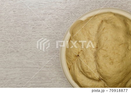 Fragment of the bowl with a raised fermented yeast dough. On the table. 70918877