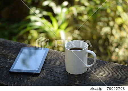 野外のテーブルの上に置いたタブレットとコーヒー 70922708
