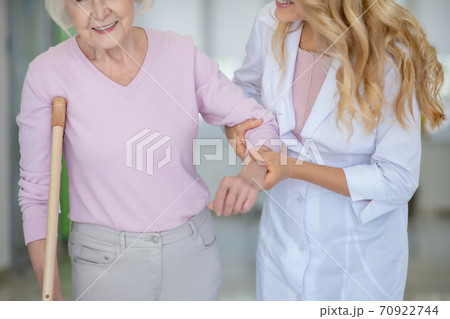 Nurse supporting an elderly woman in a pink shirt Nurse supporting an elderly woman in a pink shirt 70922744