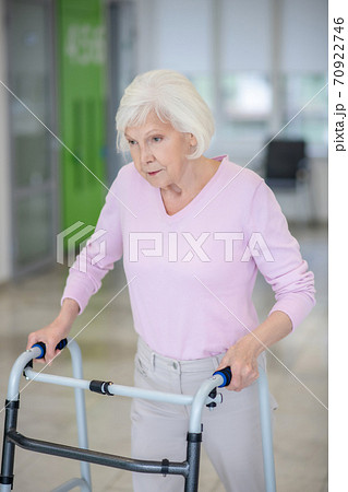 Elderly woman walking with a rolling-walker Elderly woman walking with a rolling-walker 70922746