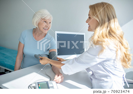 Cardiologist measuring blood-pressure to good-looking elderly woman Cardiologist measuring blood-pressure to good-looking elderly woman 70923474