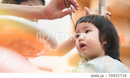Home haircut of 2 year old Asian toddler by mother in the household during Covid-19 coronavirus pandemic, self-quarantine, social distancing, DIY, mother daughter relationship, homeschool, family bond 70925716