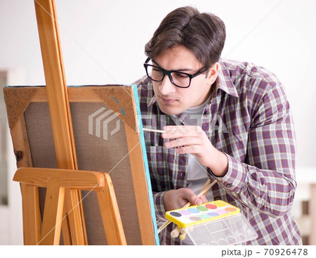 Young male artist drawing pictures in bright studio 70926478