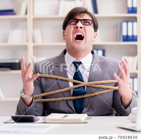 Businessman tied up with rope in office Businessman tied up with rope in office 70928630
