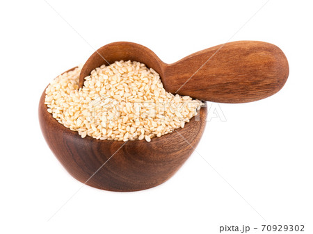 Sesame seeds in wooden bowl and spoon, isolated on white background. Organic dry sesame seeds. Sesame seeds in wooden bowl and spoon, isolated on white background. Organic dry sesame seeds. 70929302