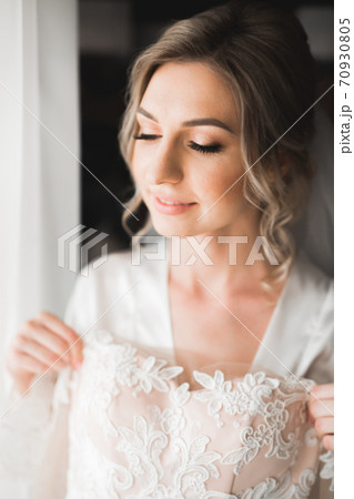Luxury bride in white dress posing while preparing for the wedding ceremony 70930805