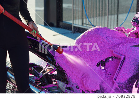 Close up high pressure pink foam washes a motorcycle at self-service car wash. Selective focus. Close up high pressure pink foam washes a motorcycle at self-service car wash. Selective focus. 70932979