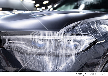 Car detailing specialist installing protective transparent foil 70933273