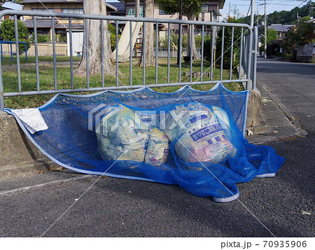 ゴミ収集所に捨てられたごみと鳥除けのためのネット 70935906