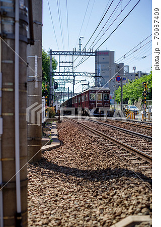 小さな踏切を通過する阪急電車 70937409