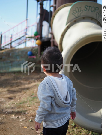 公園の滑り台を下り 遊具を見る後ろ姿の男の子の写真素材