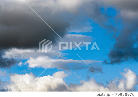 White clouds and dramatic dark thunderclouds floating across blue sky to change season weather 70938976