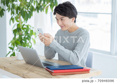 自宅で仕事をする若い男性(スマホ) 自宅で仕事をする若い男性(スマホ) 70946096