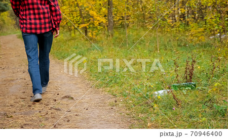 Unrecognizable man throws a plastic bottle into the grass in the forest Unrecognizable man throws a plastic bottle into the grass in the forest 70946400