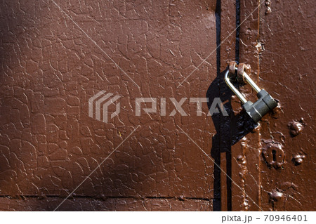 Fragment of an old brown metal gate with a lock, texture with cracks on old paint Fragment of an old brown metal gate with a lock, texture with cracks on old paint 70946401
