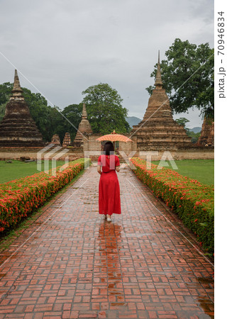 The scenery of a woman with her umbrella walking in Mahathat temple at Sukhothai, Thailand. The scenery of a woman with her umbrella walking in Mahathat temple at Sukhothai, Thailand. 70946834
