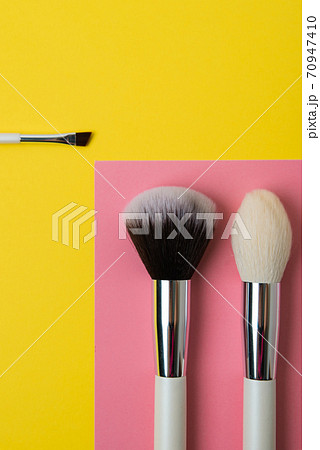 makeup brushes on a multi-colored background, pink and yellow makeup brushes on a multi-colored background, pink and yellow 70947410