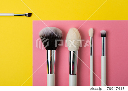 makeup brushes on a multi-colored background, pink and yellow makeup brushes on a multi-colored background, pink and yellow 70947413