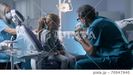 Orthodontist explaining teeth structure to little girl Orthodontist explaining teeth structure to little girl 70947940