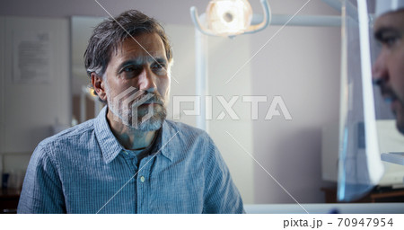Dentist examining mature male patient 70947954