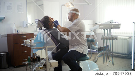 Dentist checking up teeth of mature patient Dentist checking up teeth of mature patient 70947958