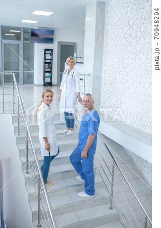 Team of smiling medical workers going upstairs Team of smiling medical workers going upstairs 70948294