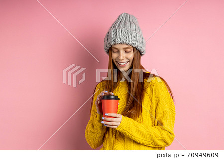 Redhead woman holding disposable cup of coffee 70949609