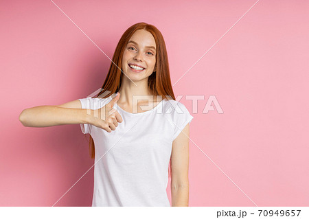 Portrait of young happy redhead woman in white t shirt 70949657