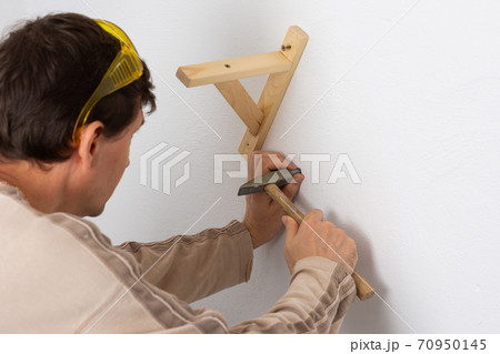 Worker scores plastic anchor with a hammer Worker scores plastic anchor with a hammer 70950145