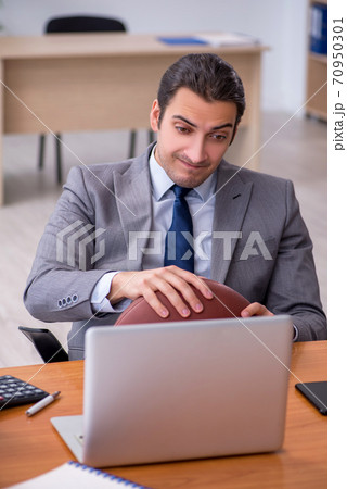 Young male employee with rugby ball in the office Young male employee with rugby ball in the office 70950301