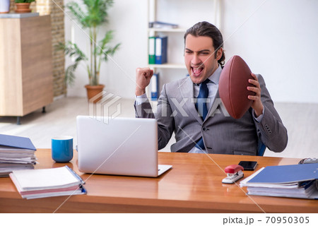 Young male employee with rugby ball in the office 70950305