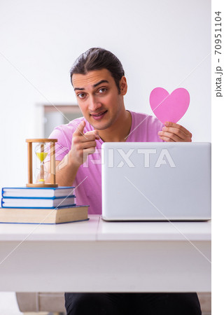 Male student in love preparing for exams in time management conc Male student in love preparing for exams in time management conc 70951104