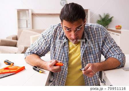Young male carpenter repairing furniture at home 70951116