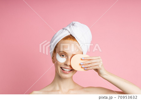 Shot of young woman applies eye patches and holding cosmetic sponge Shot of young woman applies eye patches and holding cosmetic sponge 70953632