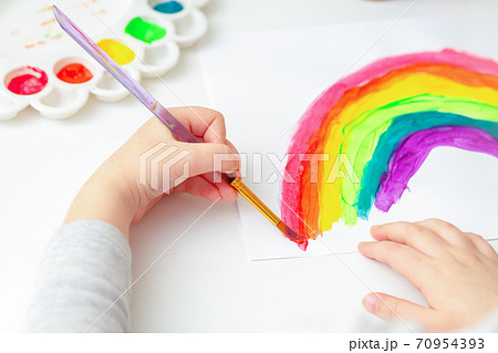 Child's hands drawing rainbow. 70954393