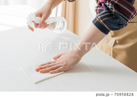 テーブルを除菌する若い女性の手の写真素材