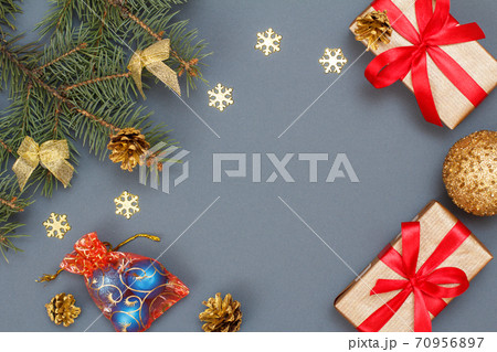 Gift boxes, fir tree branches with cones and toys on gray background Gift boxes, fir tree branches with cones and toys on gray background 70956897