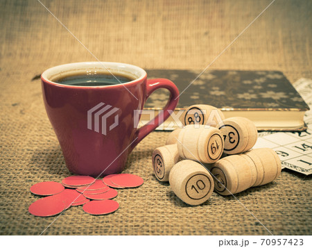 Wooden lotto barrels, cards, chips and cup of coffee on sackcloth. Wooden lotto barrels, cards, chips and cup of coffee on sackcloth. 70957423