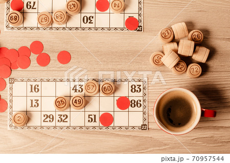 Wooden lotto barrels, game cards, red chips and cup of coffee Wooden lotto barrels, game cards, red chips and cup of coffee 70957544