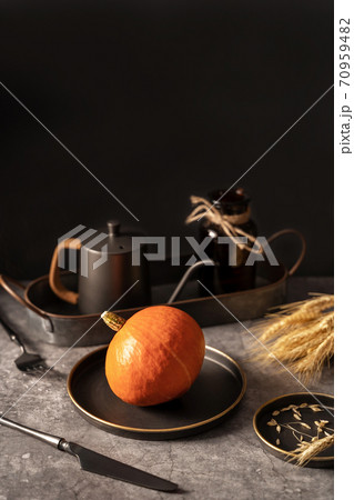Vintage template with old metal tableware, ripe pumpkin and ear of wheat on black stone background for concept design. Fall concept. Vintage template with old metal tableware, ripe pumpkin and ear of wheat on black stone background for concept design. Fall concept. 70959482