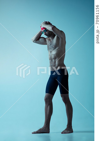 Professional male swimmer with hat and goggles in motion and action, healthy lifestyle and movement concept. Neoned style. Professional male swimmer with hat and goggles in motion and action, healthy lifestyle and movement concept. Neoned style. 70961156
