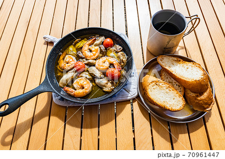 キャンプの朝食のアヒージョとフランスパンの写真素材