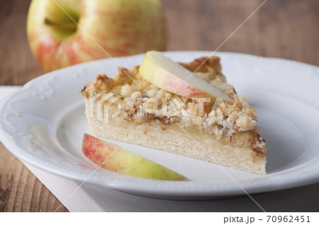 Piece of pie with apples and streusel  on a white plate 70962451