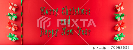 Panorama Christmas gift box with red ribbon and green ribbon on red background with merry christmas and Happy new year text for background 70962632